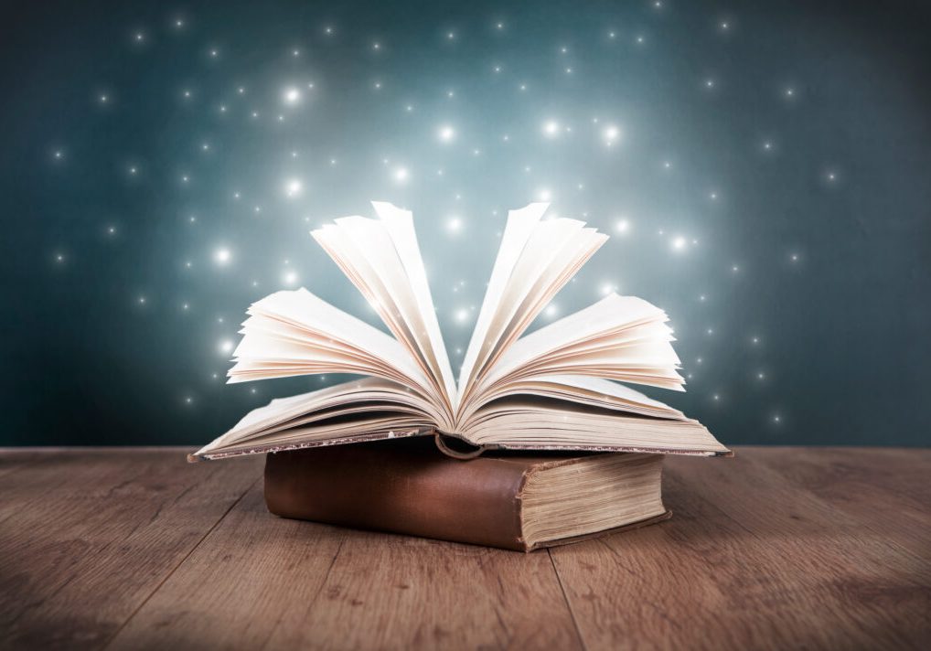 an old open book on a table in front of a blackboard